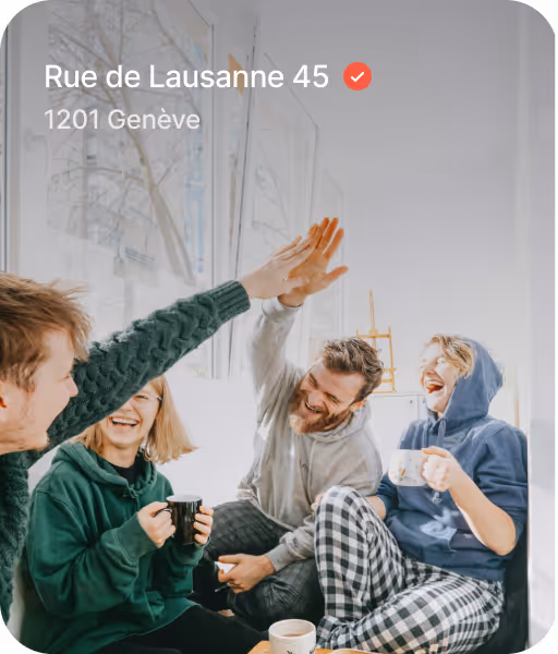 Four friends in casual clothes smiling and giving a high five while sitting indoors with coffee cups.